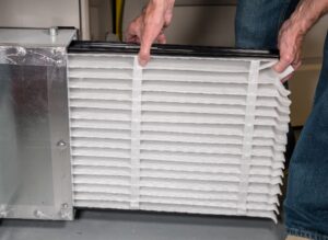 person changes air filter in furnace