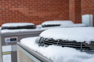 Outdoor mechanical air conditioning units idling during the winter with snow on top of the fans